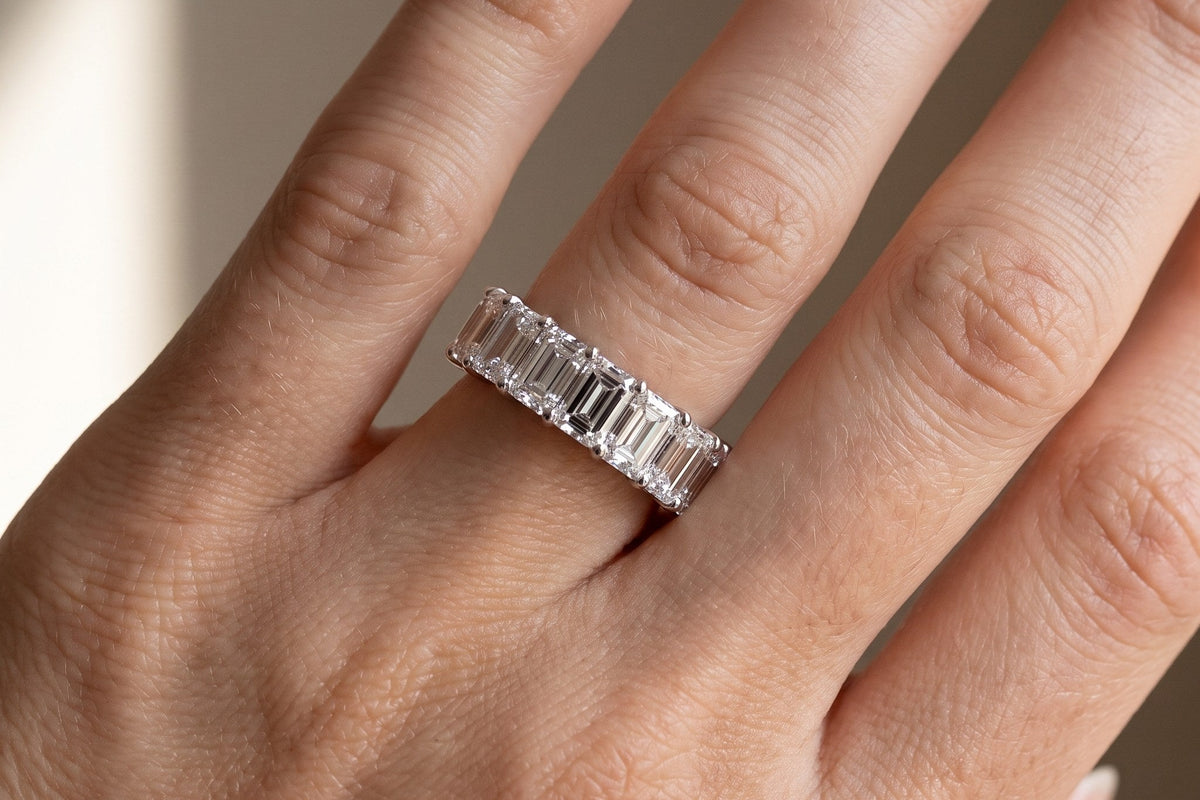 Hand wearing an emerald cut lab grown diamond eternity band in white gold, close up, Draco Diamond