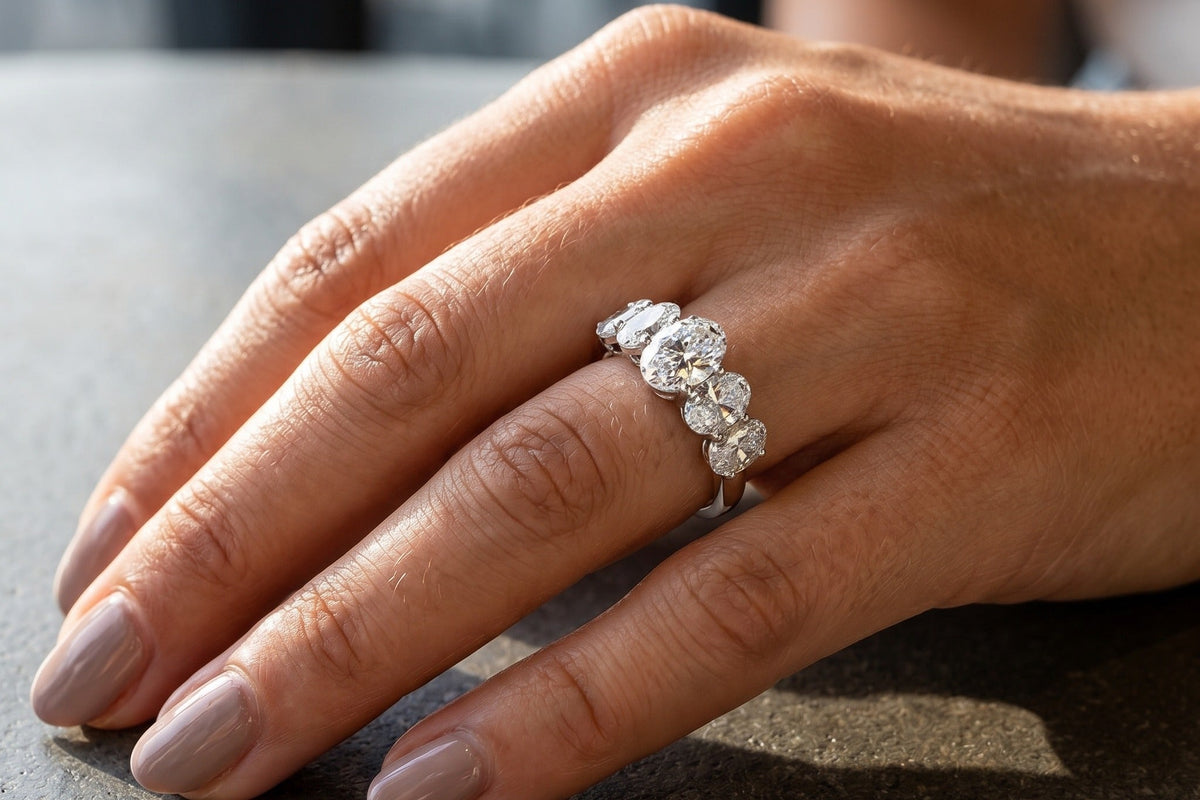 Hand resting on stone wearing a five stone oval lab grown diamond anniversary band in soft daylight, Draco Diamond