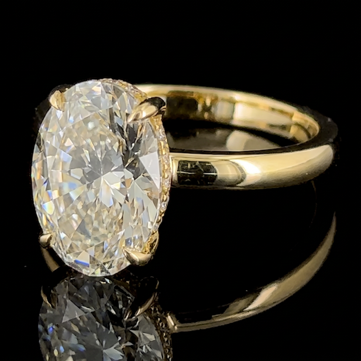 3ct oval lab grown diamond ring, 14k yellow gold, macro on black, four claws holding the oval