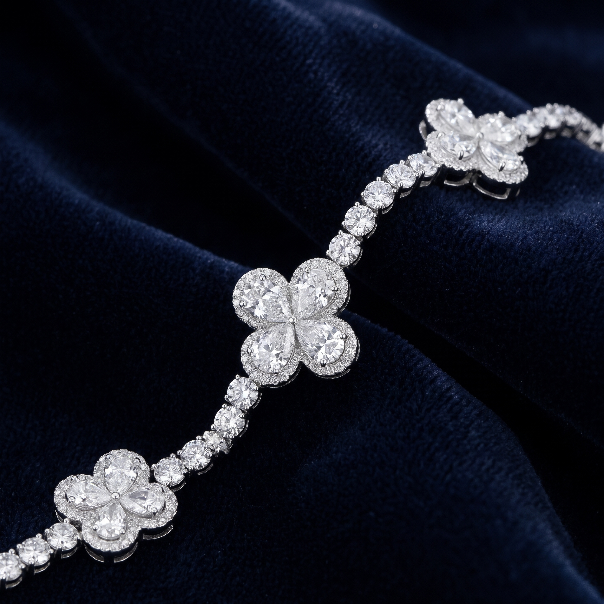13ct pear clover lab grown diamond tennis bracelet draped on navy velvet, clovers spaced