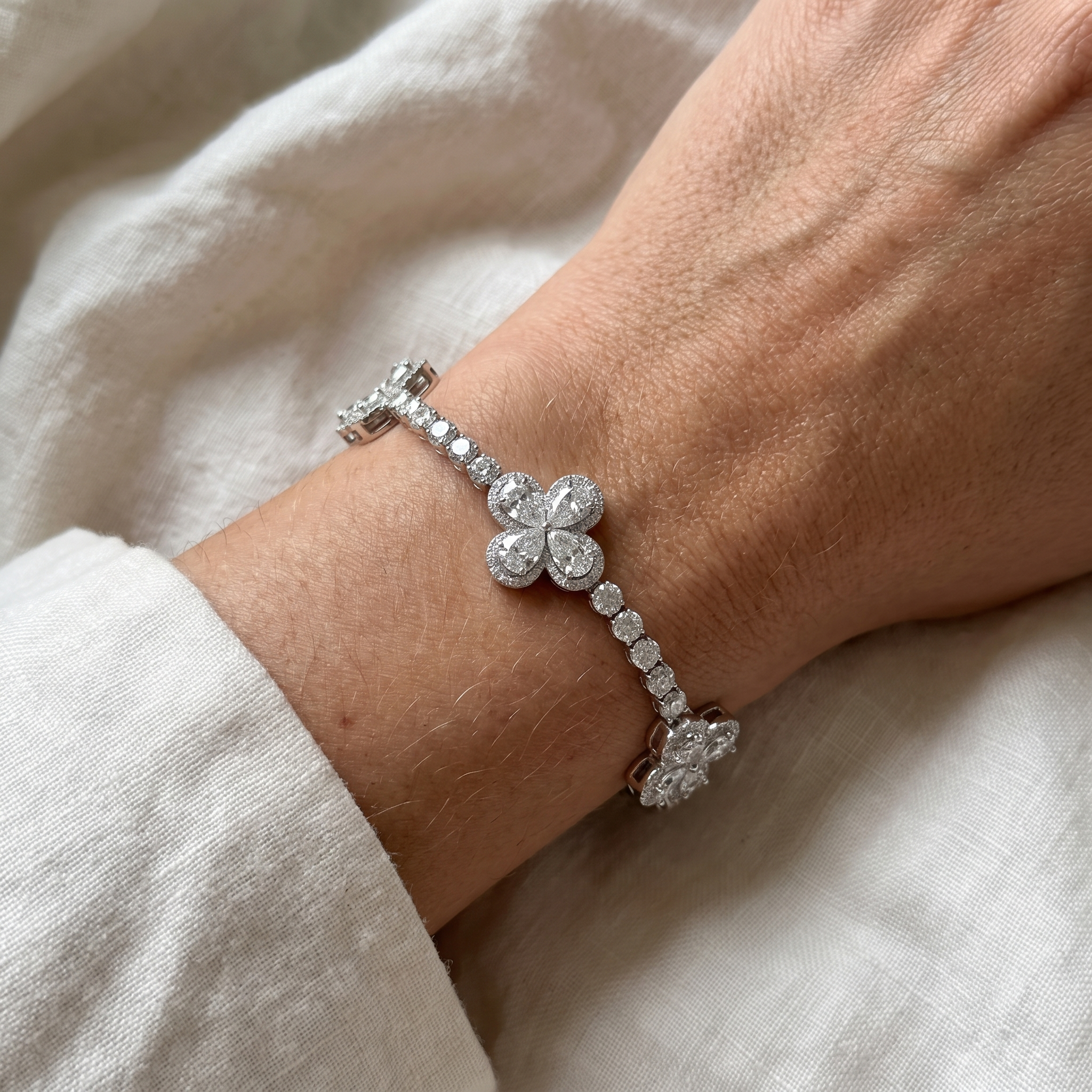 13ct pear clover lab grown diamond tennis bracelet close editorial on a womans wrist, spaced