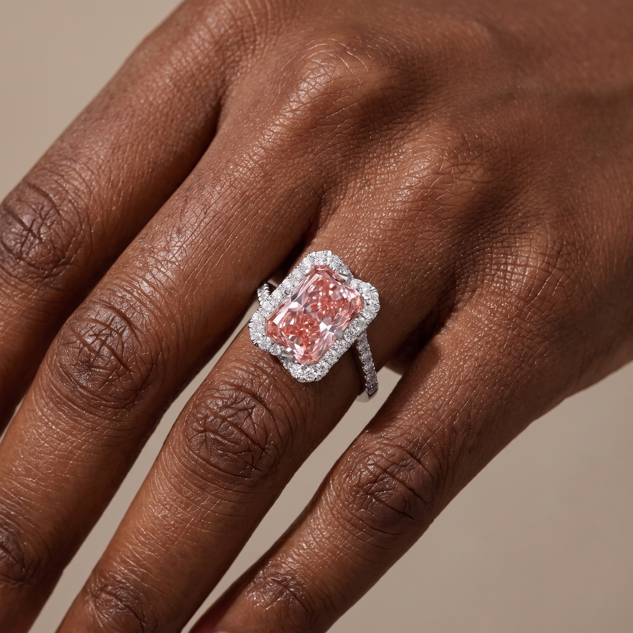 5ct fancy pink radiant lab grown diamond ring worn on the hand, bypass band with one pave strand each side and a white diamond halo