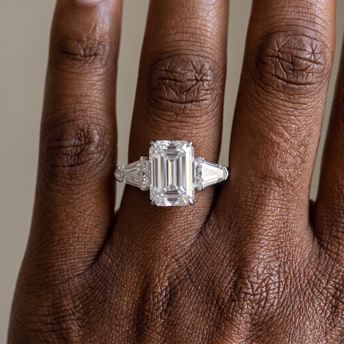 5ct emerald cut lab grown diamond ring with shield side stones worn on the hand, three quarter view
