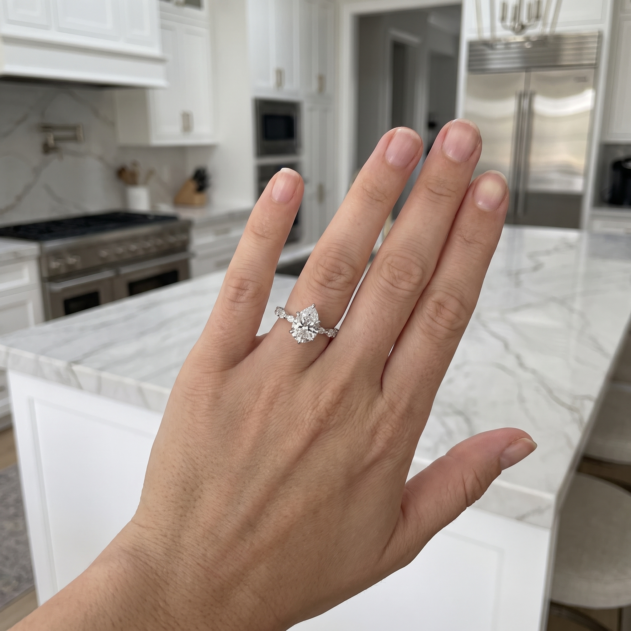 customer showing 2.5ct pear lab diamond engagement ring, luxury kitchen
