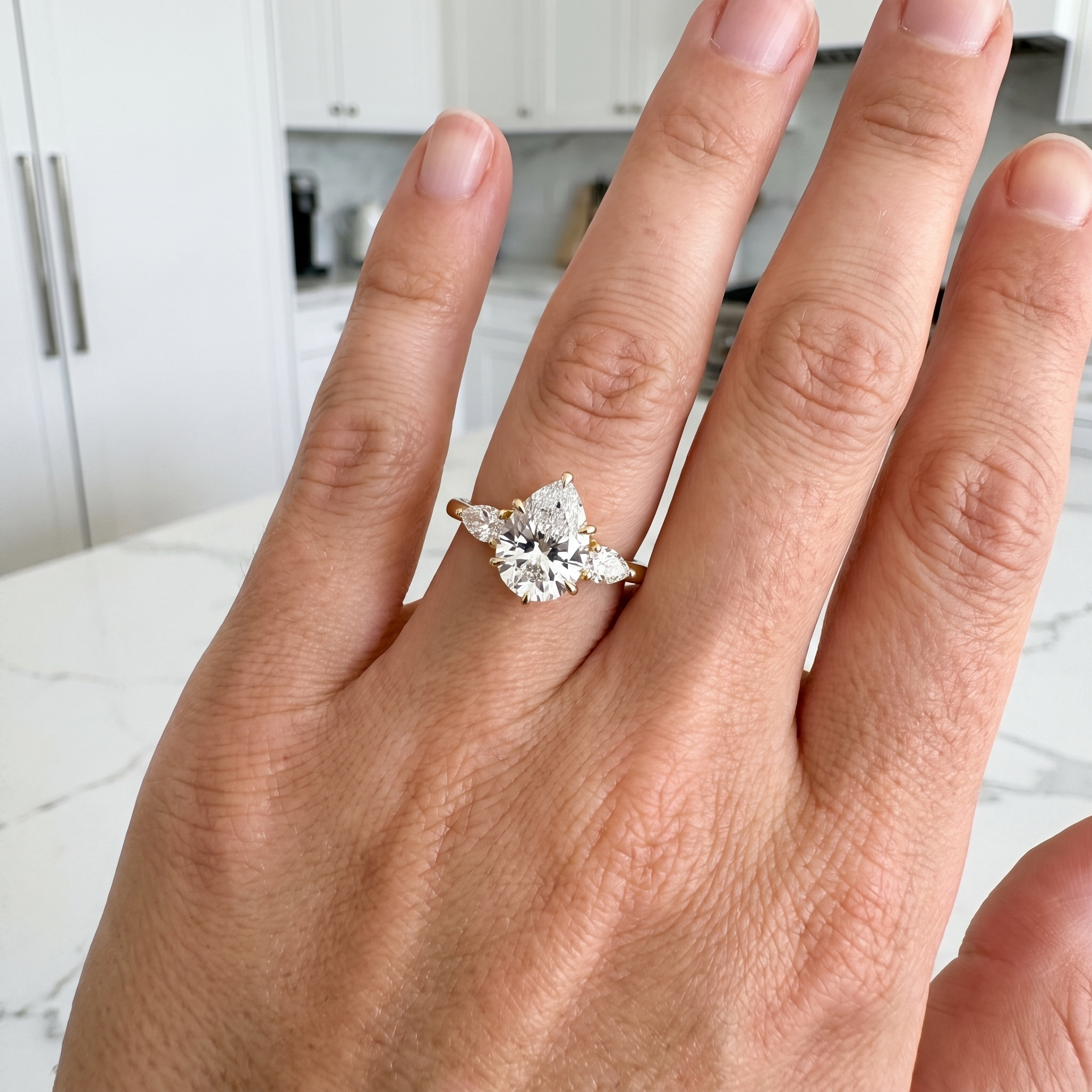 customer showing 2ct pear lab diamond three stone ring, white kitchen