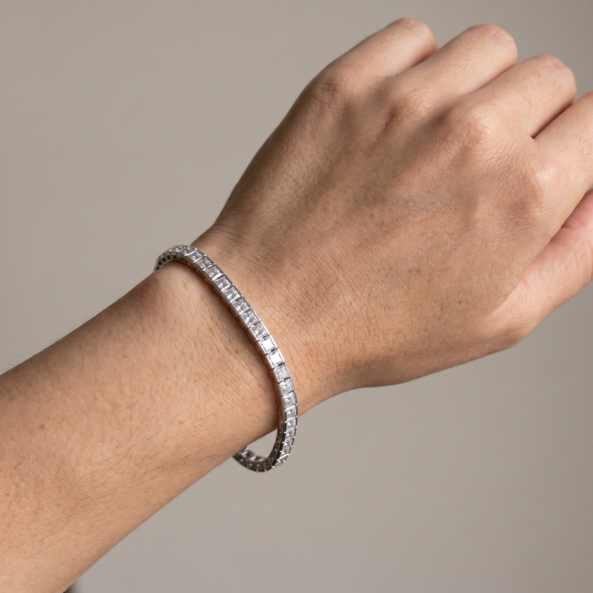 7ctw bezel set princess cut lab grown diamond tennis bracelet worn on the wrist, three-quarter view
