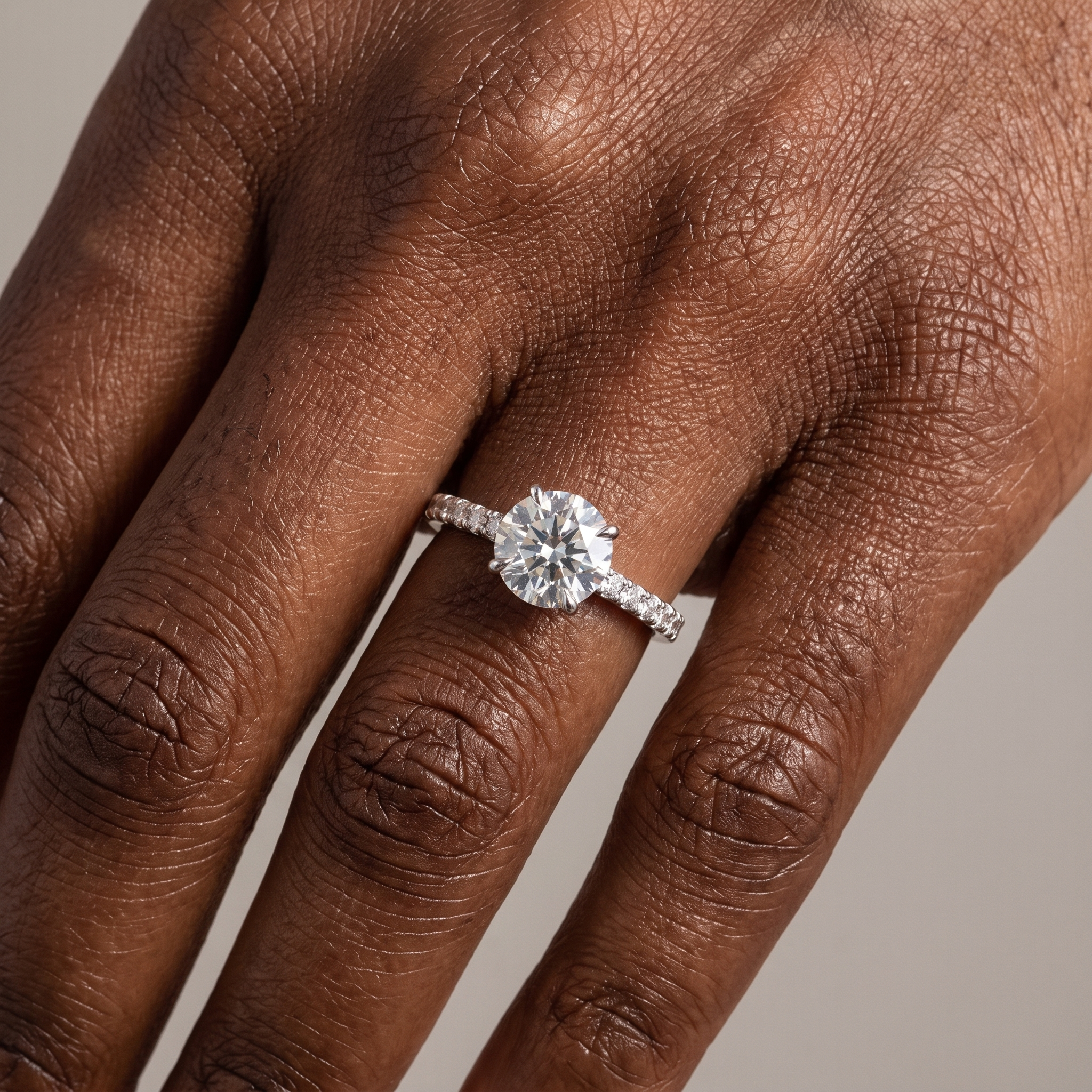 2ct round brilliant lab grown diamond engagement ring with hidden halo worn on the hand, pave shoulders visible