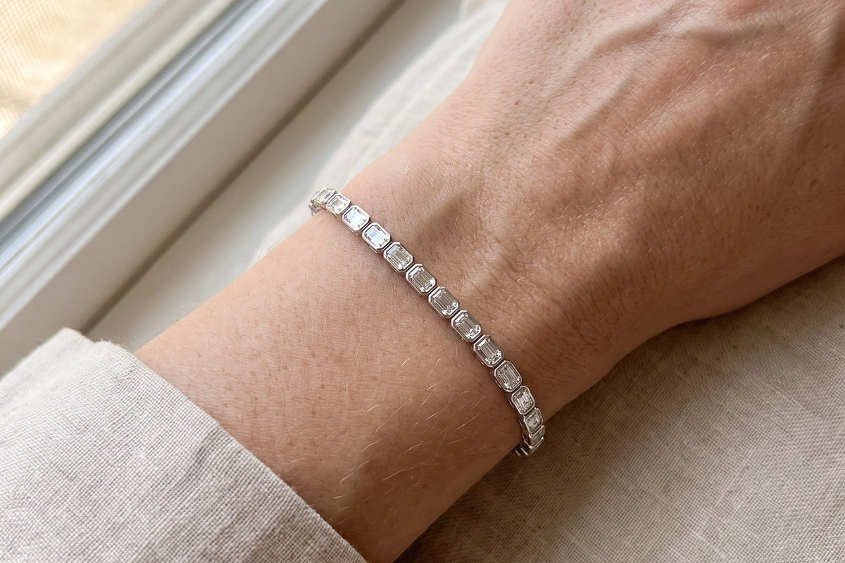 Emerald cut lab grown diamond tennis bracelet worn on a wrist beside a bright window, showing the straight edge to edge line of step cut stones, Draco Diamond
