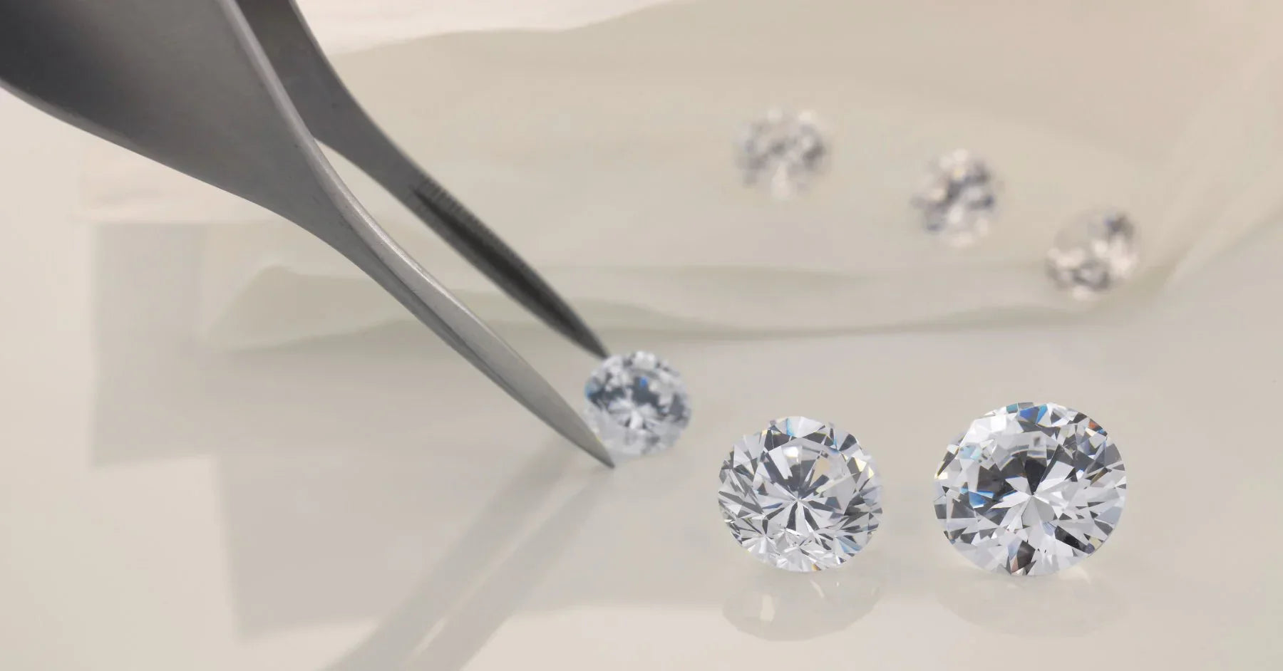 Loose IGI certified round brilliant lab grown diamonds selected with jeweler's tweezers during a Draco Diamond catalog review