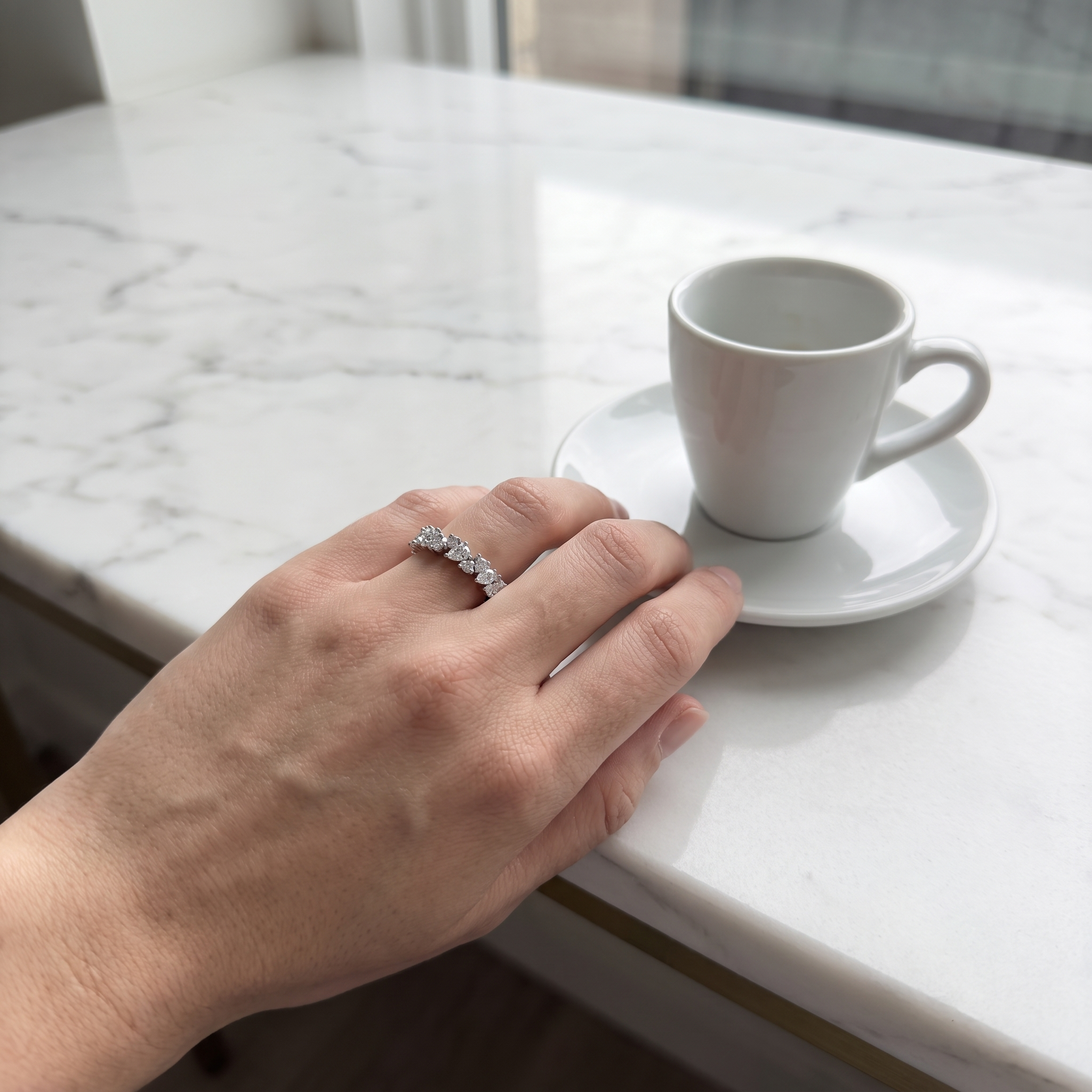 customer wearing pear and round cluster lab diamond band, marble counter