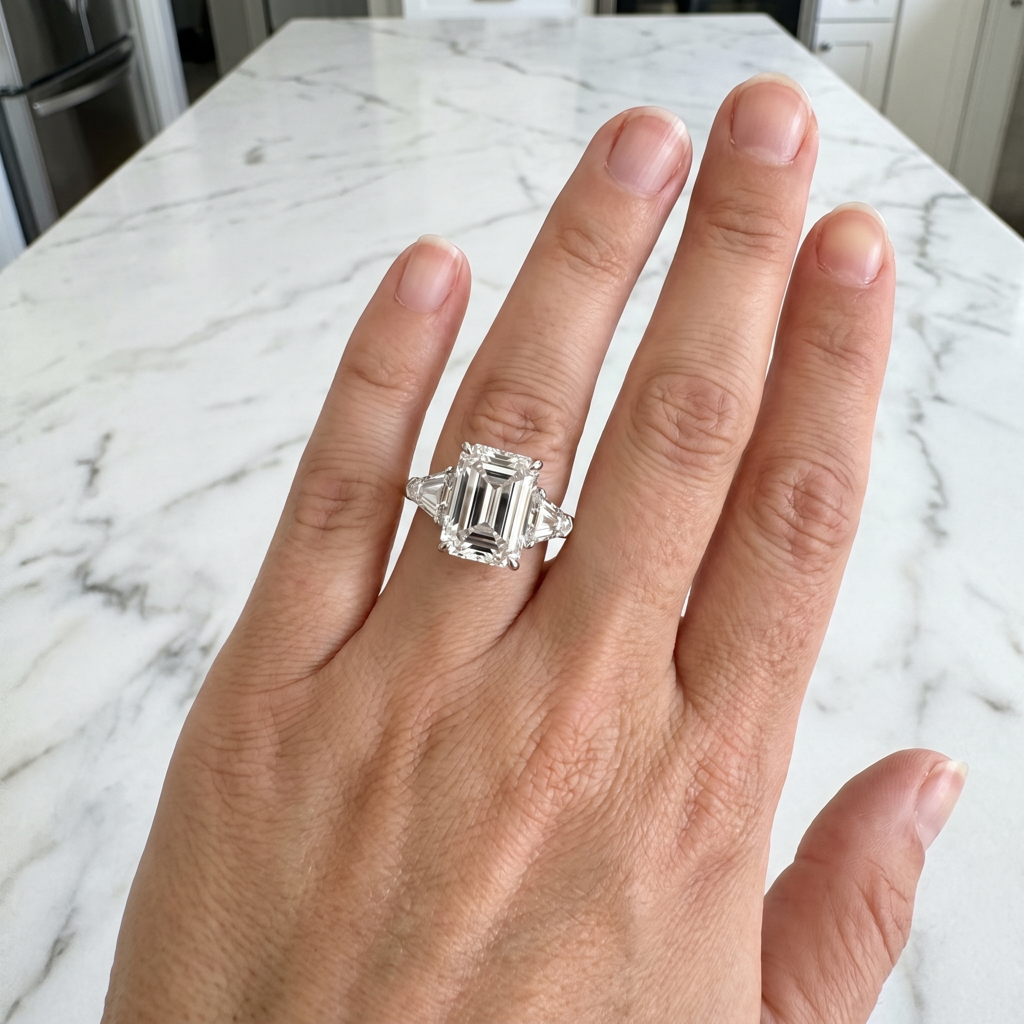customer showing 5ct emerald cut lab diamond ring, luxury kitchen marble