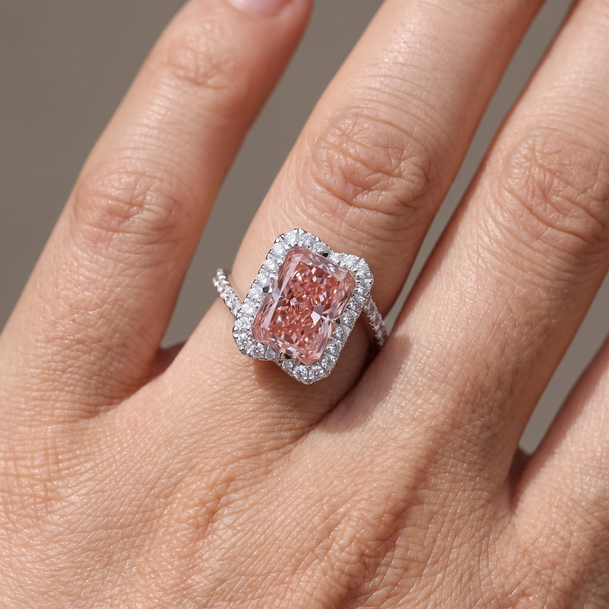 5ct fancy pink radiant lab grown diamond ring worn on the hand, split shank bypass band and white diamond halo