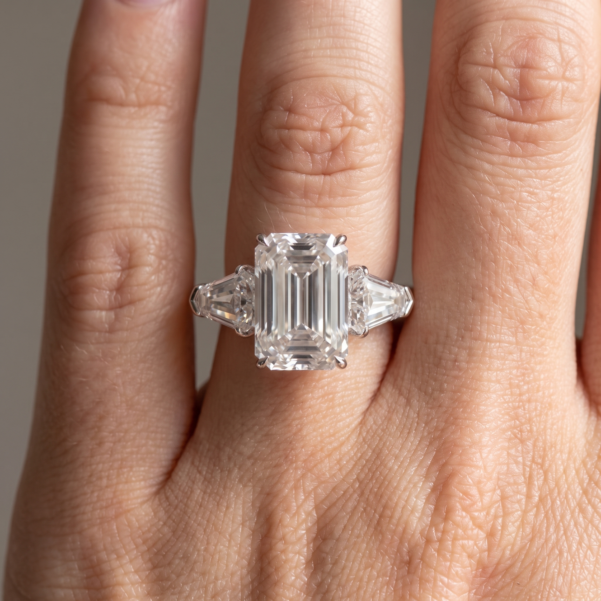 5ct emerald cut lab grown diamond ring with shield side stones worn on the hand, front view