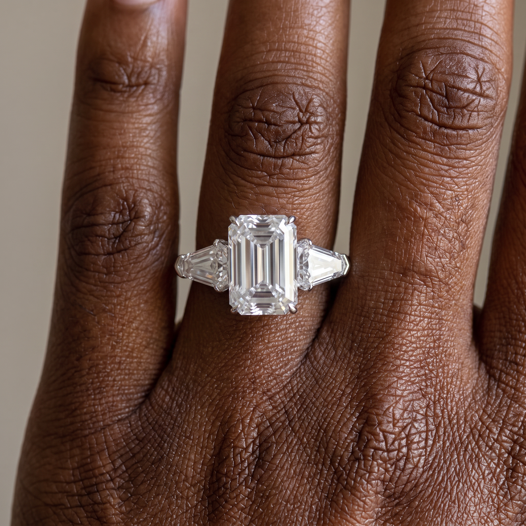 5ct emerald cut lab grown diamond ring with shield side stones worn on the hand, three quarter view
