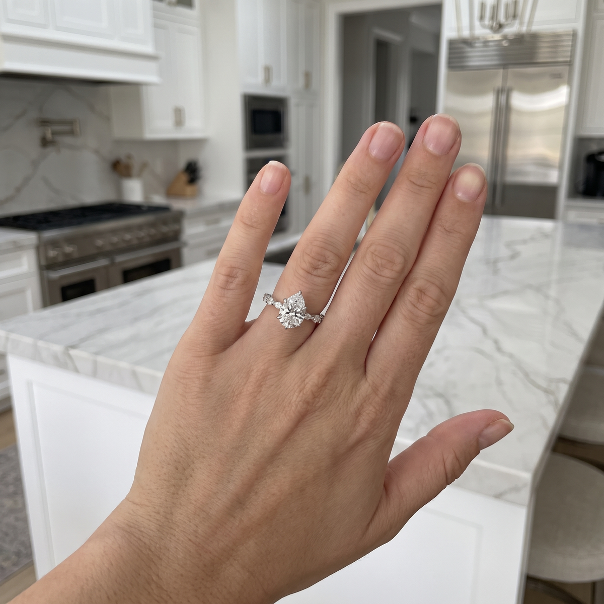 customer showing 2.5ct pear lab diamond engagement ring, luxury kitchen