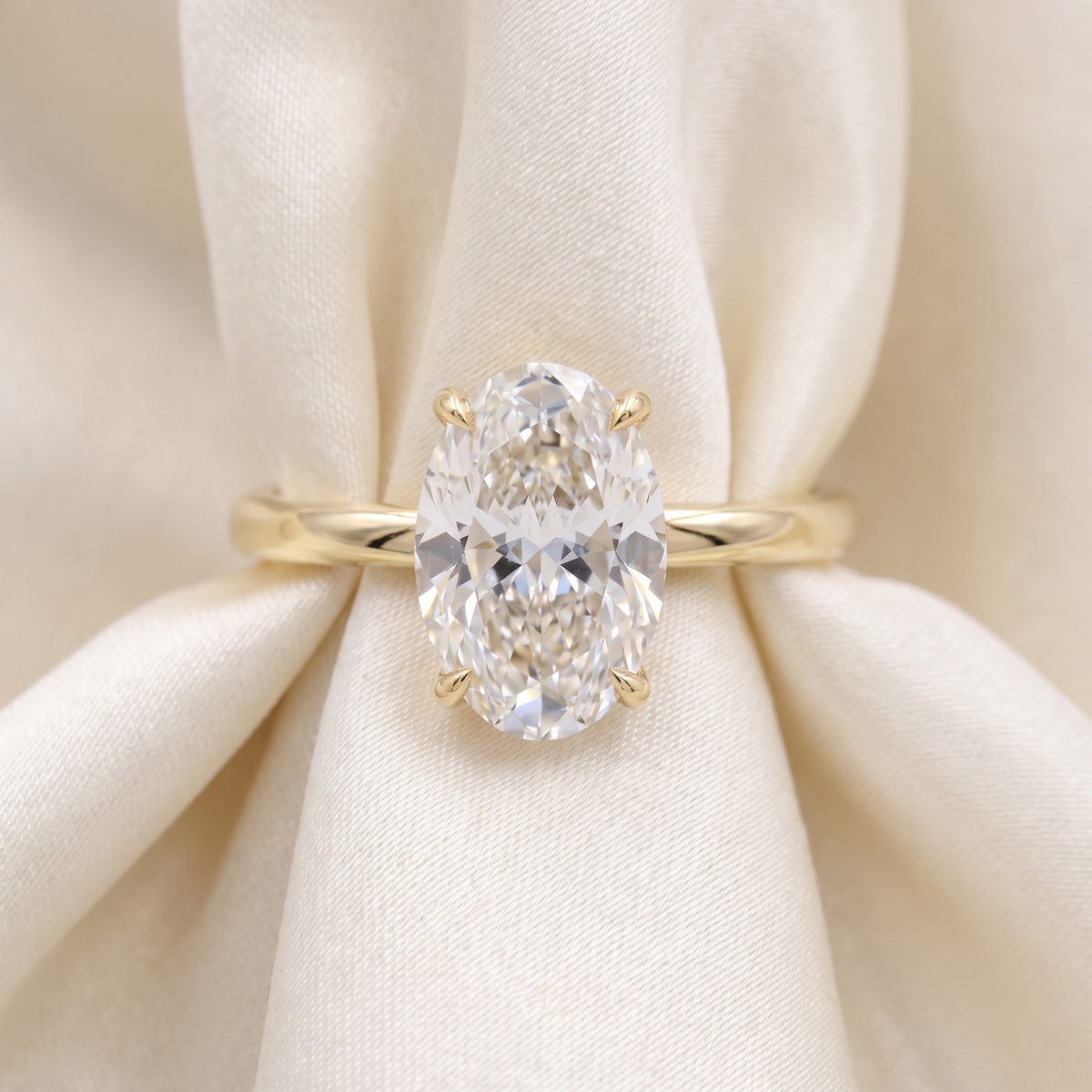 3ct oval lab grown diamond engagement ring, 14k yellow gold, on ivory silk