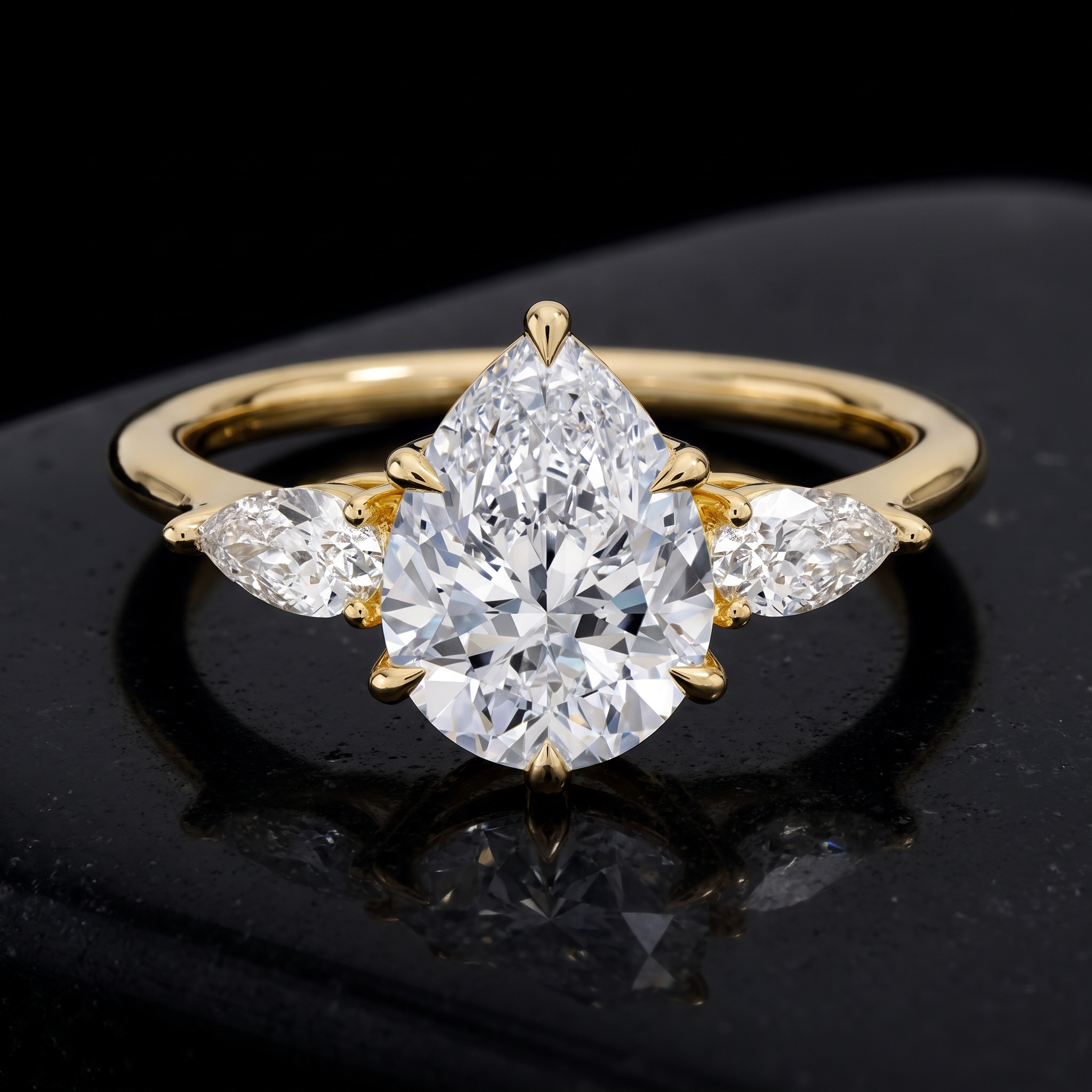 pear lab diamond three stone ring with pear side stones, three quarter view on black